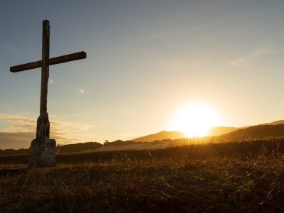 brown cross on green grass field during sunset